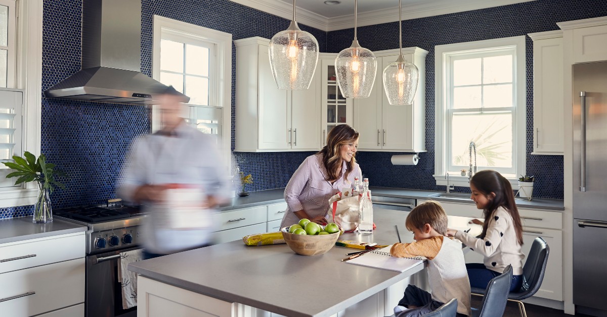 Image of a mom helping her two young children with homework at the kitchen island with beautiful pendant lights hanging down