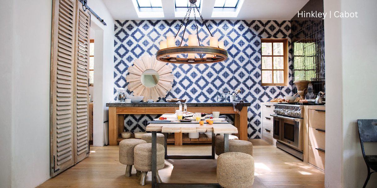 A kitchen with a blue and white tile backsplash. There is a chandelier in the center of the room over a kitchen table that is set for breakfast.