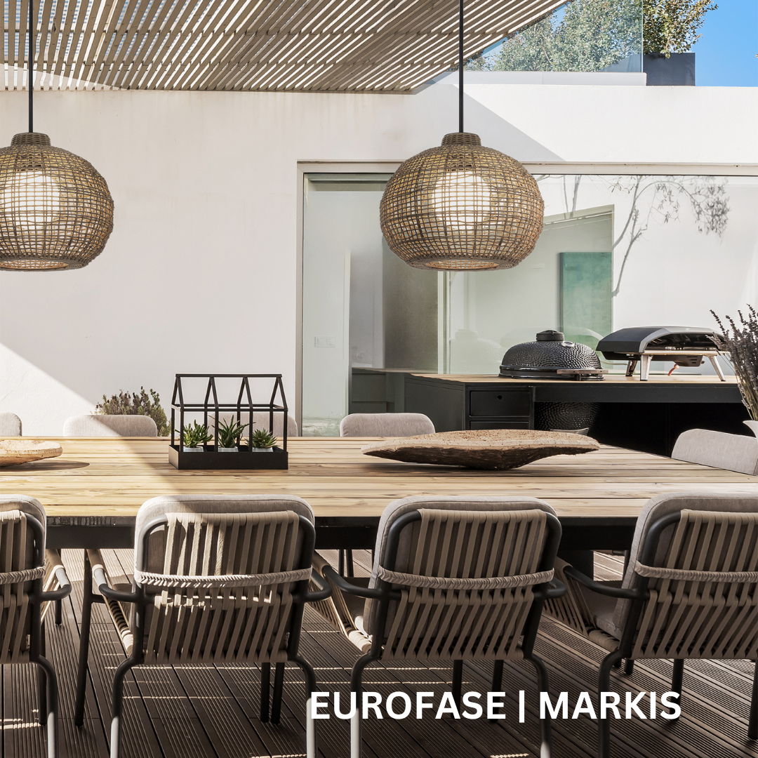 Two wicker pendant lights hanging above a wooden table on an outdoor deck.