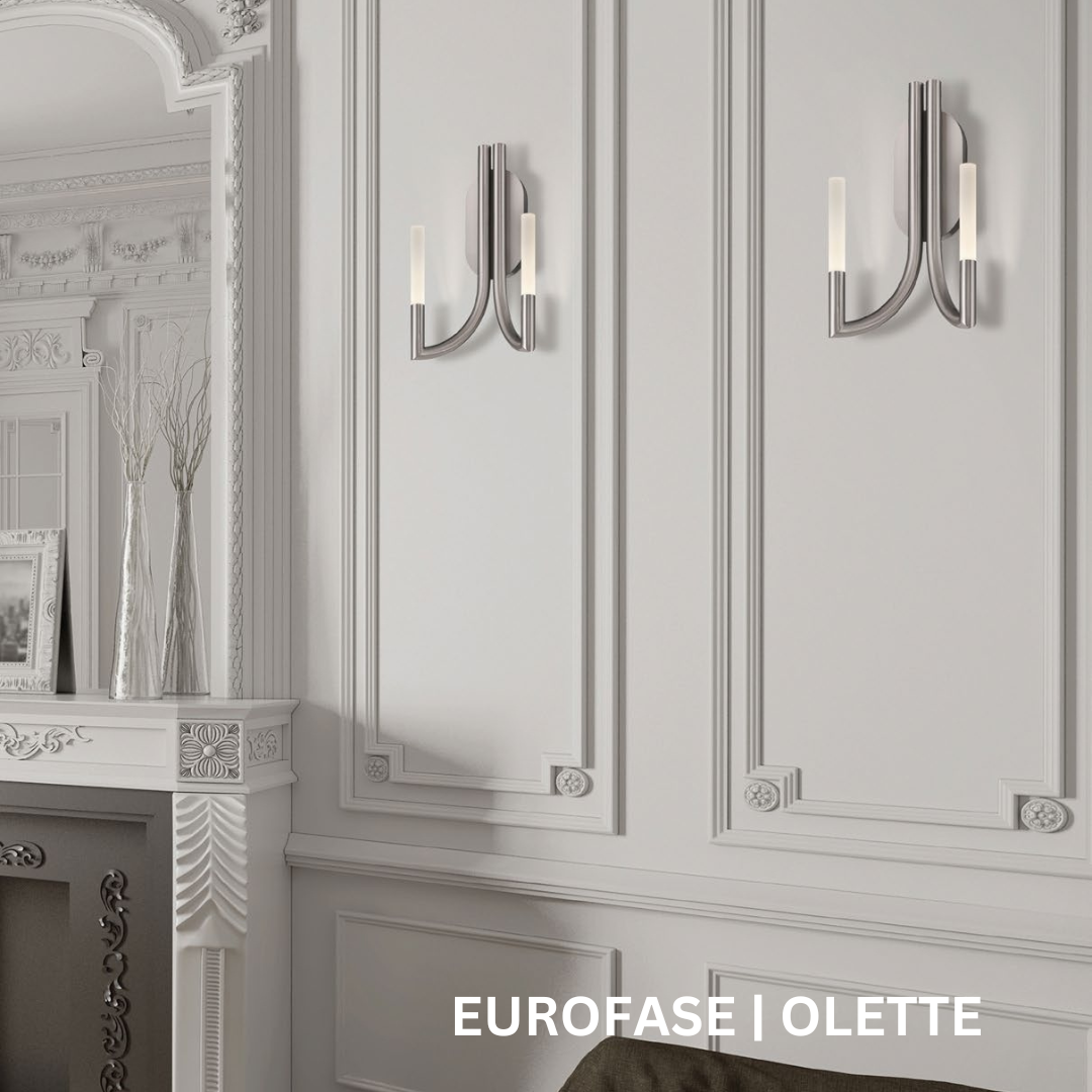 Silver two-pronged wall sconce on a white wall with ornate detailing.