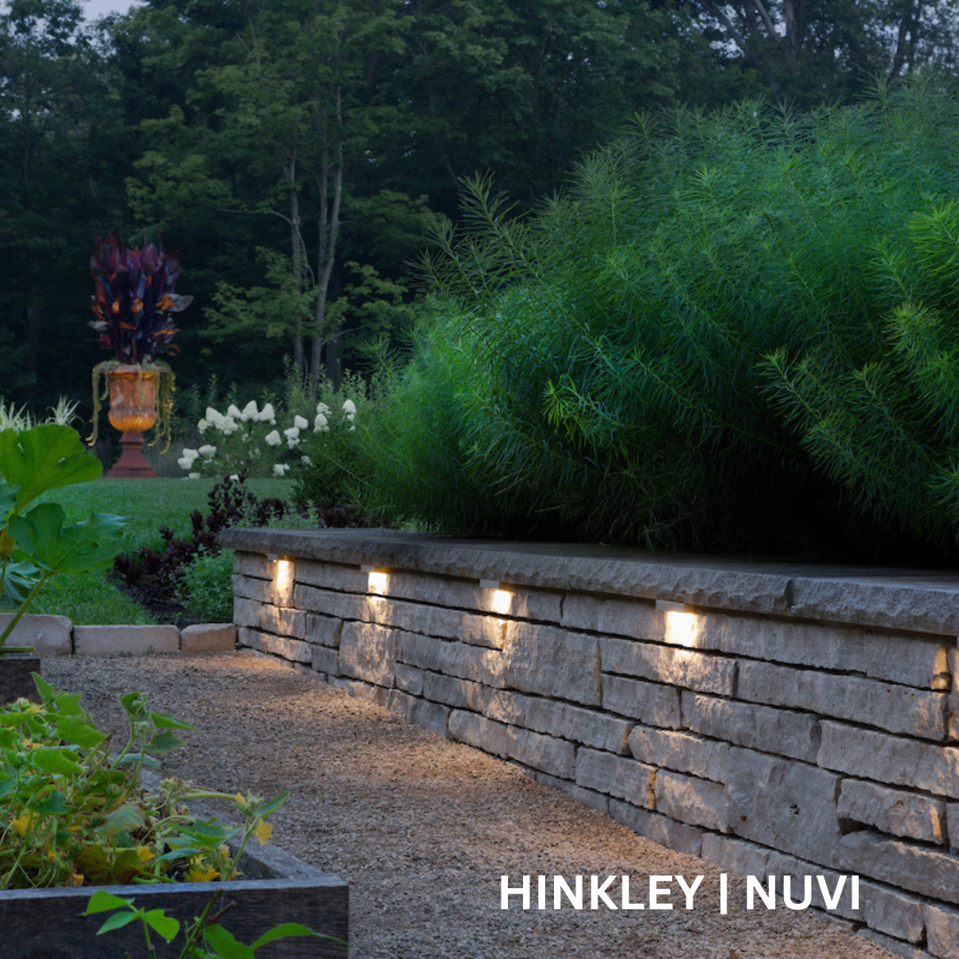 Outdoor path with a knee-high, light gray wall running along it. There are rectangular lights embedded into the wall.