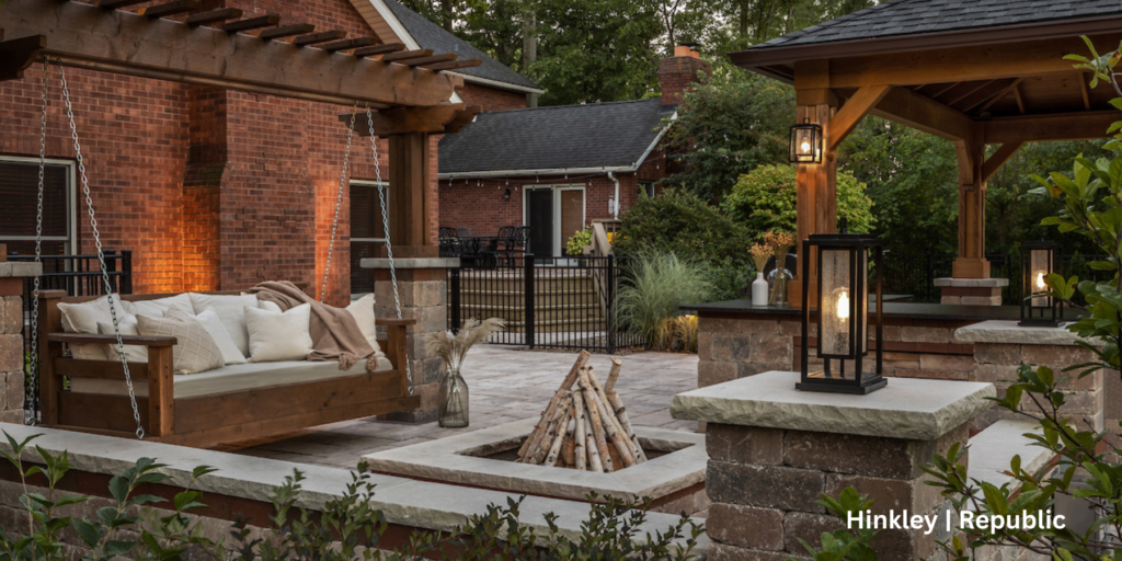 Outdoor living space with a couch swing, fire pit, and gazebo. There are lighting fixtures placed around the space.