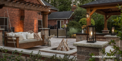 Outdoor living space with a couch swing, fire pit, and gazebo. There are lighting fixtures placed around the space.