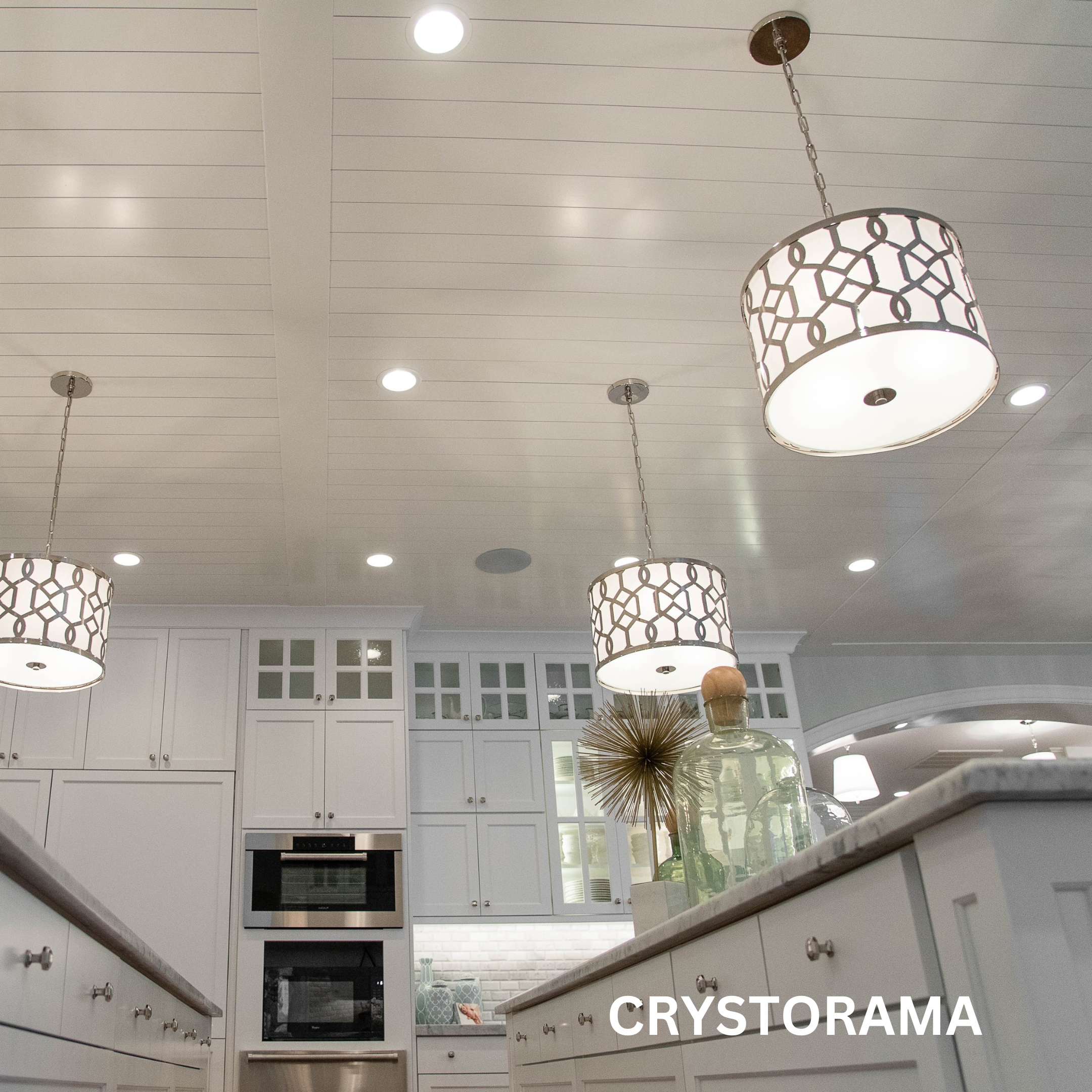 3 pendant lights with metal design frames hanging in a kitchen.